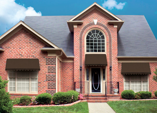 Brick home with Sunbrero awnings over windows